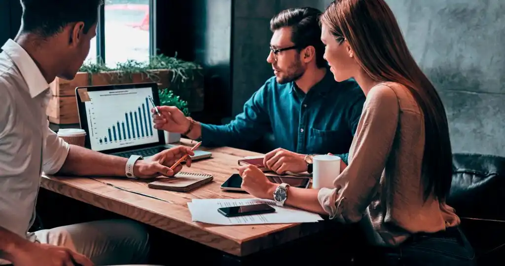 Equipo de ventas y mercadeo en una junta revisando cómo hacer la estrategia de sinergia.