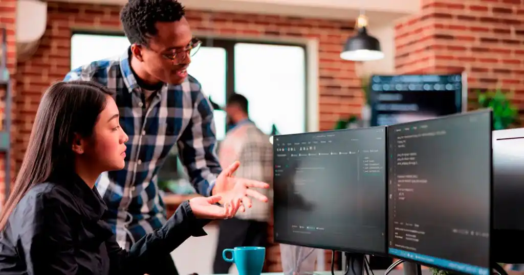 Dos personas evaluando un sistema de seguridad informática en una secuencia de código que aparece en un monitor.